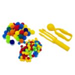 Kit Pinça e Pompons da Materiais para Brincar, mostrando uma pinça de plástico sendo usada para pegar um pompom colorido, com outros pompons de diferentes tamanhos e cores ao lado.