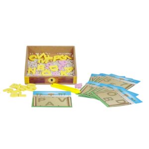 Jogo Baú do Tesouro da Materiais para Brincar, mostrando um baú de madeira aberto com pérolas douradas e peças de letras e números. Uma pinça está sendo usada para pegar uma das peças.