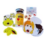Kit Caras e Bocas da Materiais para Brincar, mostrando um rosto impresso com uma das bocas de EVA acoplada, e um balão de fala com uma palavra escrita, mostrando como o jogo funciona.