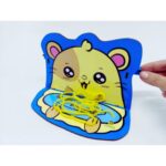 Kit Enrola Macarrão da Materiais Para Brincar, mostrando um suporte de MDF com desenho de porco e lã sendo enrolada ao seu redor.