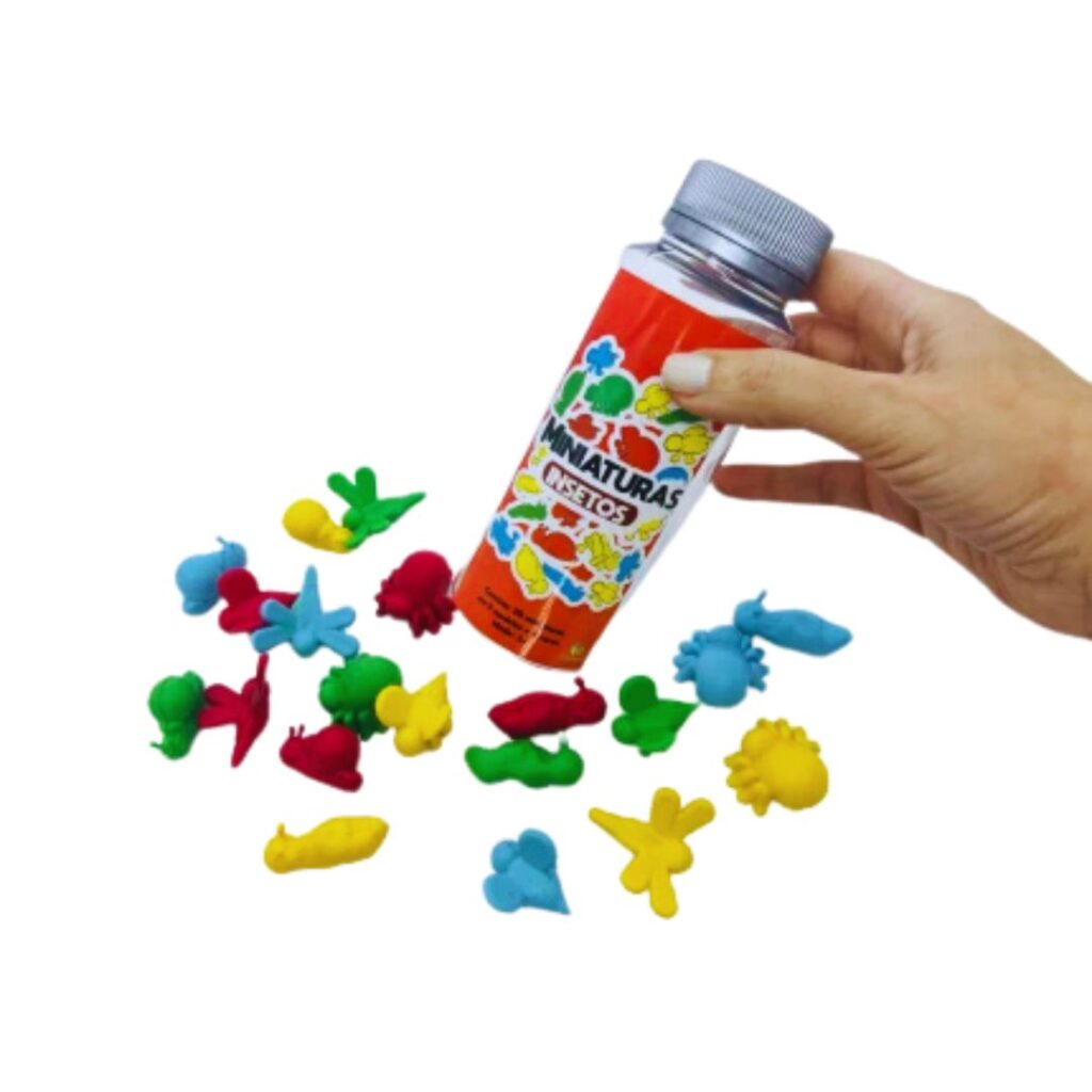 Kit Miniaturas Insetos da Materiais Para Brincar, mostrando o pote vermelho com algumas das miniaturas de insetos espalhadas ao redor. As miniaturas, em cores vibrantes, estão organizadas por tipo ou cor, como um grupo de formigas azuis.
