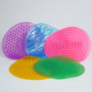 Kit Tapete Sensorial da Materiais Para Brincar, mostrando os 5 tapetes coloridos e texturizados (com pontinhos, ondas, etc.) dispostos lado a lado no chão. Uma criança pode estar descalça sobre um dos tapetes.