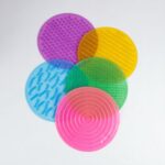 Kit Tapete Sensorial da Materiais Para Brincar, mostrando os 5 tapetes coloridos e texturizados (com pontinhos, ondas, etc.) dispostos lado a lado no chão. Uma criança pode estar descalça sobre um dos tapetes.